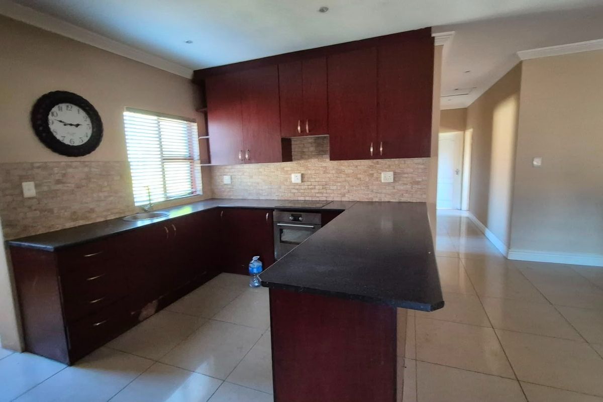 A functional kitchen featuring dark wood cabinetry, stone countertops, built-in oven, and tiled backsplash, offering a clean layout ready for modern updates.