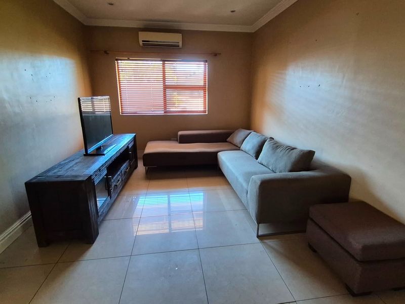 A living room featuring tiled flooring, an air conditioning unit, and venetian blinds, offering a functional space with neutral wall finishes.