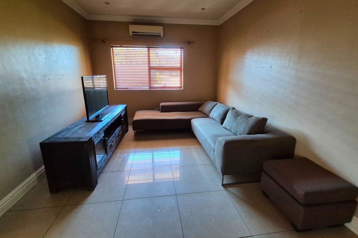 A living room featuring tiled flooring, an air conditioning unit, and venetian blinds, offering a functional space with neutral wall finishes.