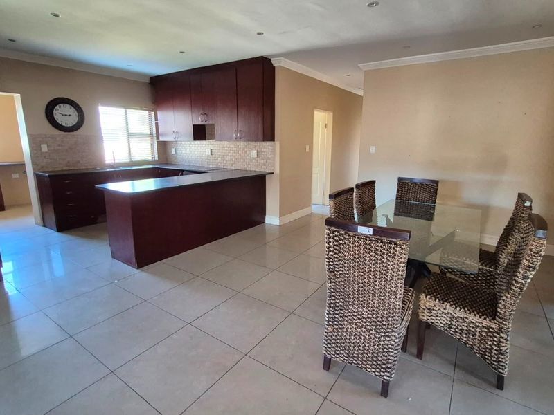 Open-plan living and dining area featuring dark wood kitchen cabinetry, tiled flooring, and recessed lighting, creating a functional and connected living space.