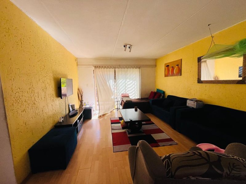 A living room featuring laminate flooring, textured yellow walls, and a sliding glass door providing access to the exterior.