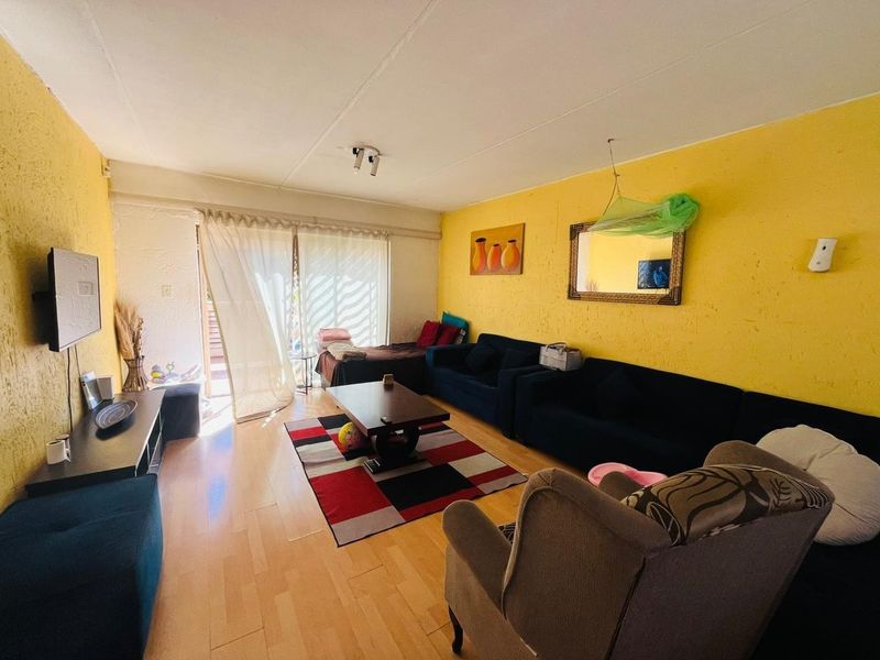 A living room featuring laminate flooring and a sliding glass door leading to an outdoor area, with bright yellow textured walls.