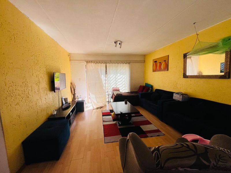 A living room featuring laminate flooring, textured yellow walls, and a sliding glass door providing access to the exterior.