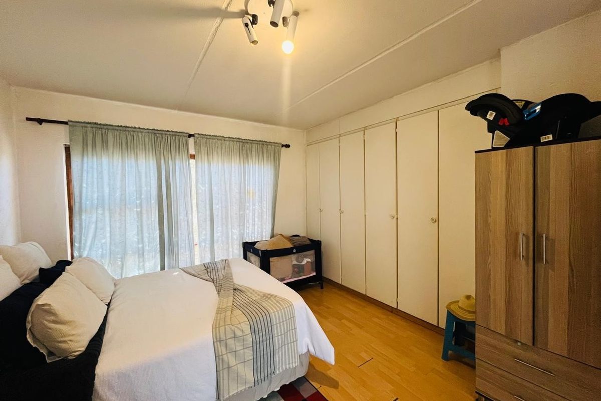 A bedroom featuring laminate flooring and extensive built-in cupboard storage, providing a functional and neutral space.