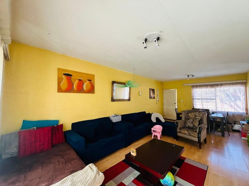 A living room featuring laminate flooring and textured yellow walls, offering a functional space with potential for modern updates.