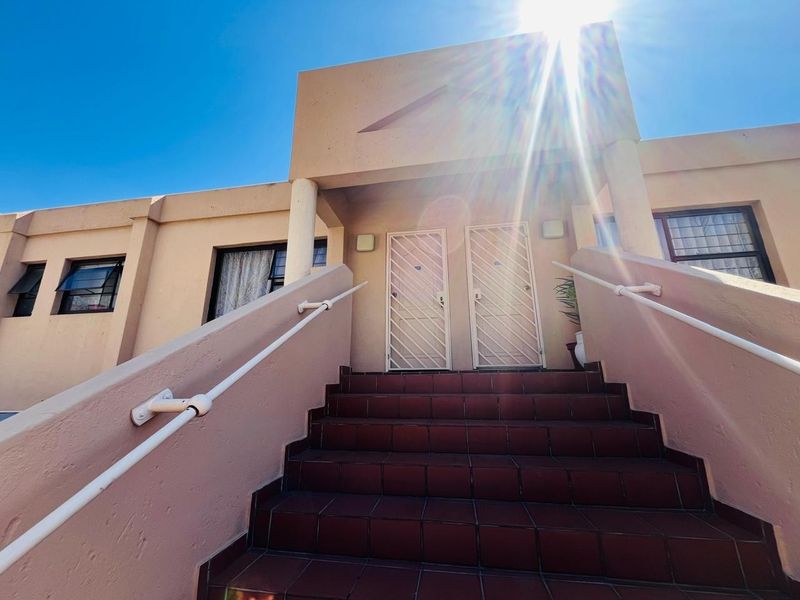 Front exterior view of the property featuring a tiled staircase leading to dual entrance doors with security gates and window bars.