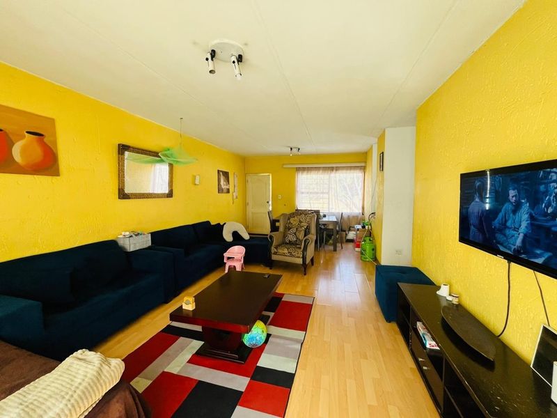 Open plan living and dining area featuring laminate flooring and bright yellow walls, providing a functional space for relaxation and meals.