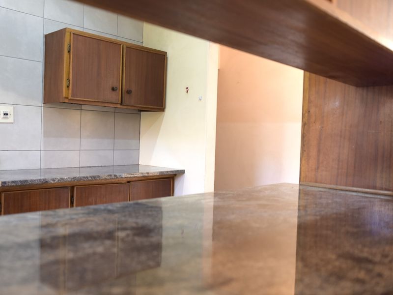 A functional kitchen area featuring dark wood-look cabinetry, granite countertops, and a neutral tiled backsplash, offering a clean and practical workspace.