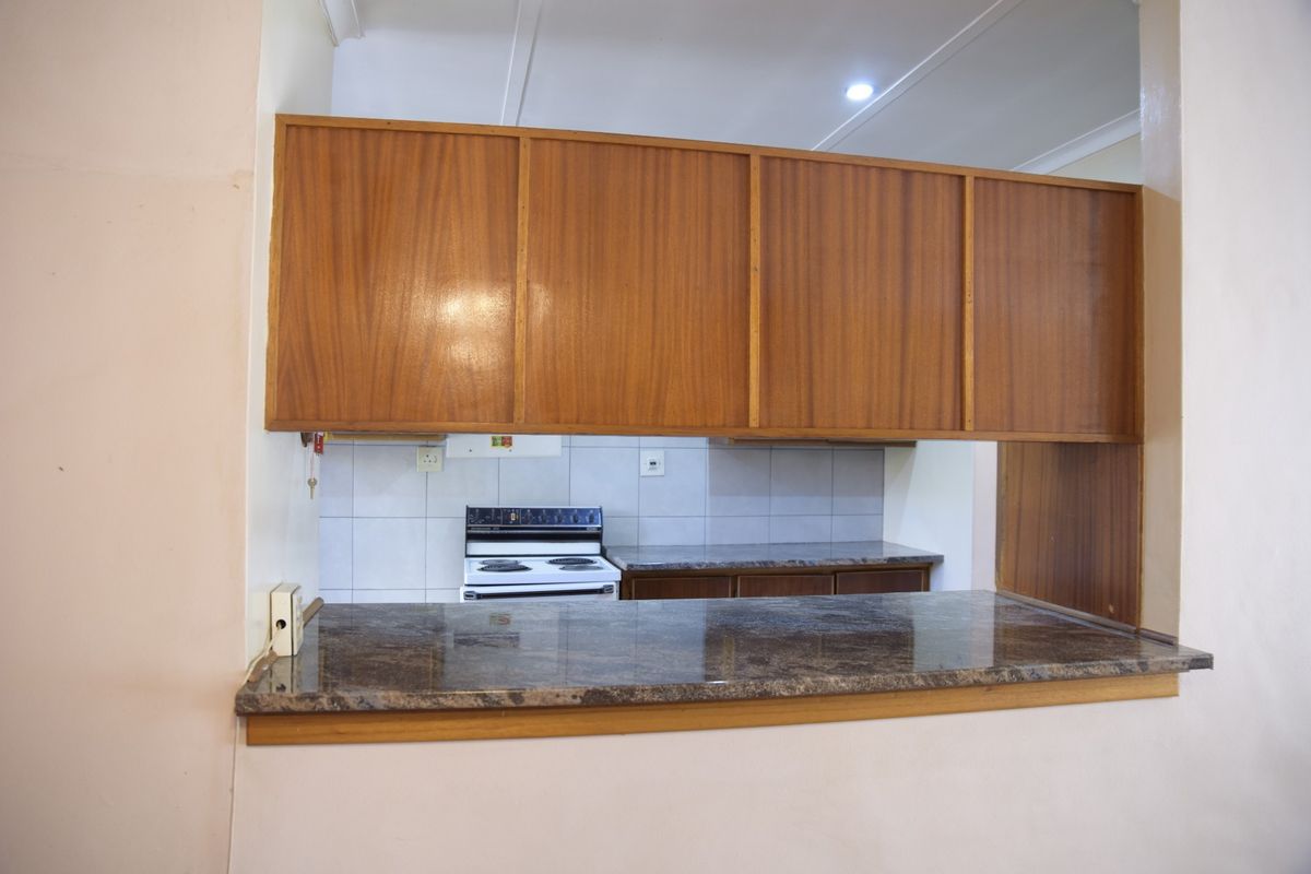 A functional kitchen featuring wooden cabinetry, granite countertops, and a breakfast bar pass-through, providing a practical layout for cooking and casual dining.