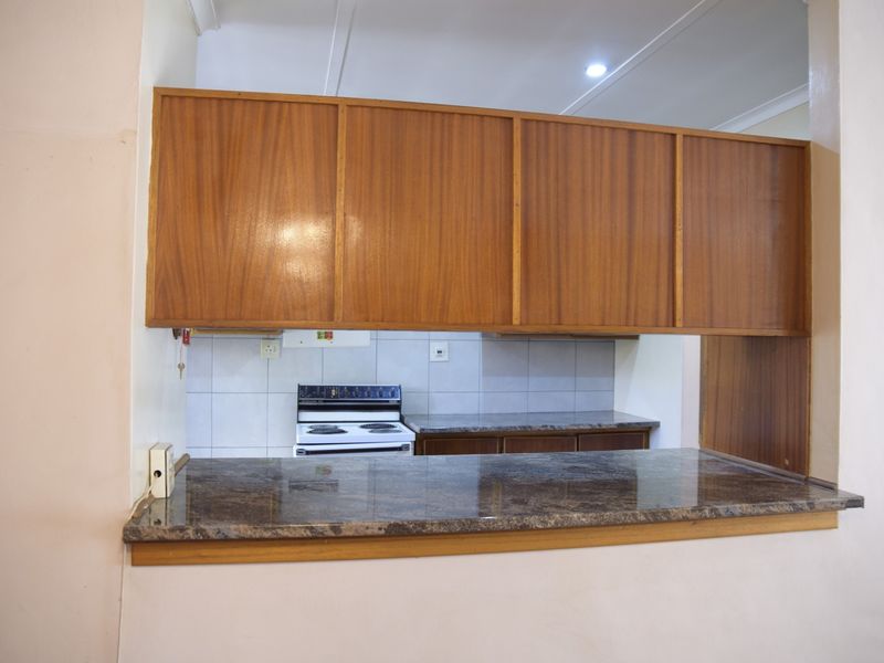 A functional kitchen featuring wooden cabinetry, granite countertops, and a breakfast bar pass-through, providing a practical layout for cooking and casual dining.