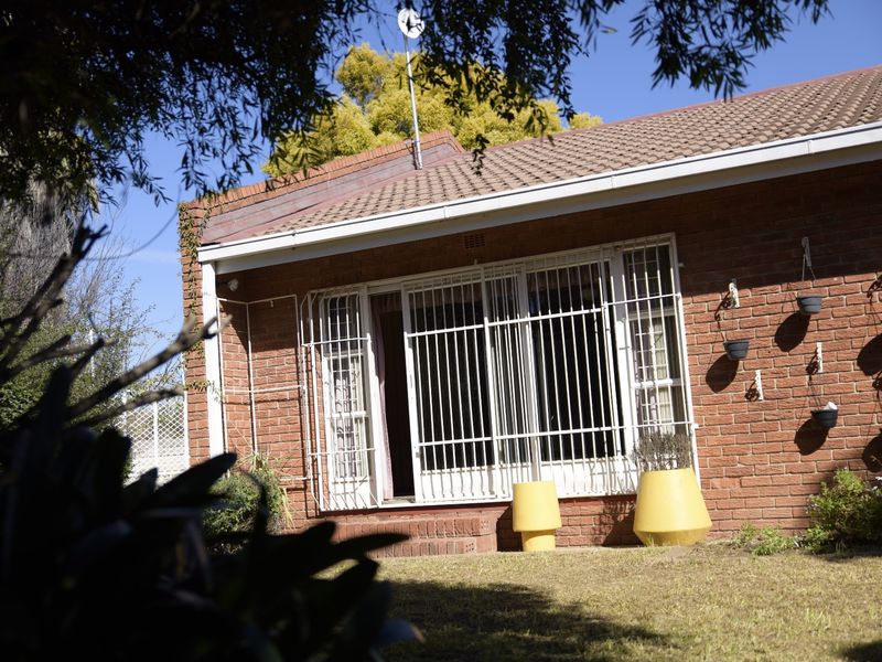 Rear view of the townhouse featuring a face brick facade, tiled roof, and secure sliding door access to the garden area.