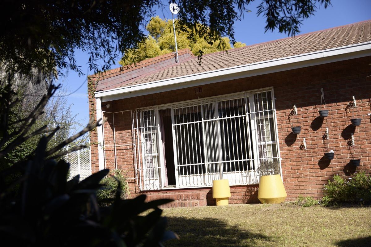 Rear view of the townhouse featuring a face brick facade, tiled roof, and secure sliding door access to the garden area.