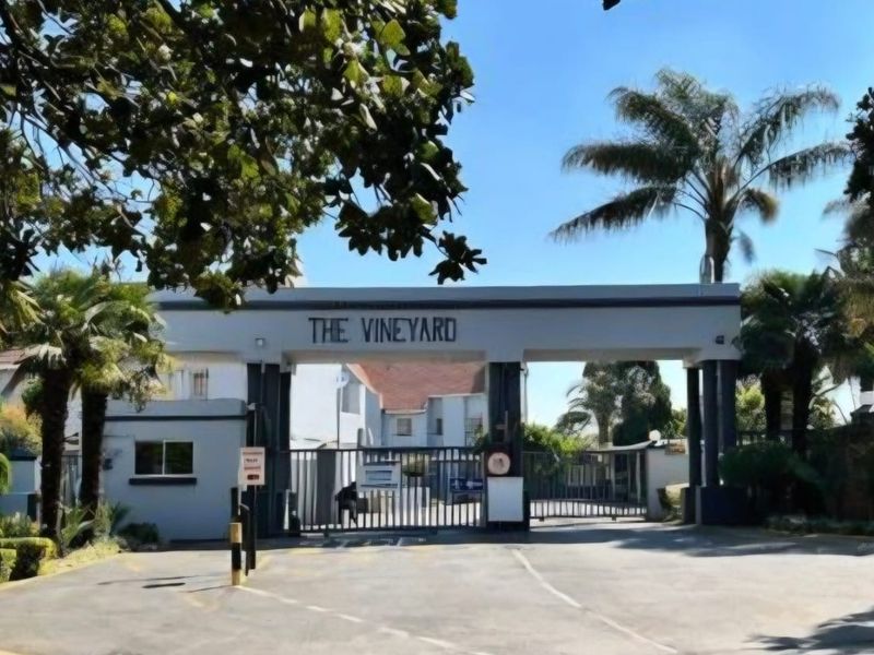 The main entrance gate and security access point for The Vineyard townhouse complex, featuring a gated driveway and structural gatehouse.