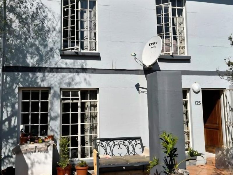 Front facade of a townhouse featuring a tiled entrance area, security-barred windows, and an installed satellite dish.