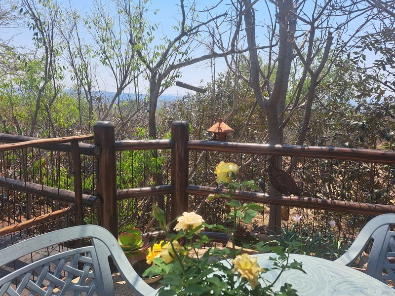 An elevated outdoor patio area featuring a rustic timber railing and wire mesh fencing, overlooking a natural wooded landscape.