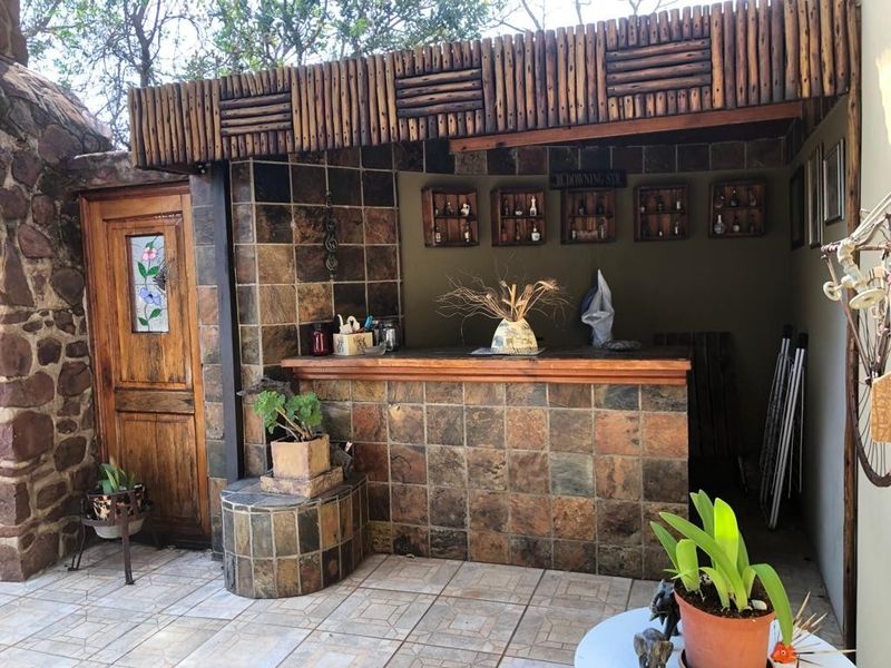 Outdoor entertainment area featuring a built-in bar with stone tile finishes, timber roof structure, and a decorative stained glass door.