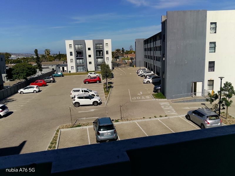 An elevated view of an apartment complex parking lot and surrounding residential building facades.