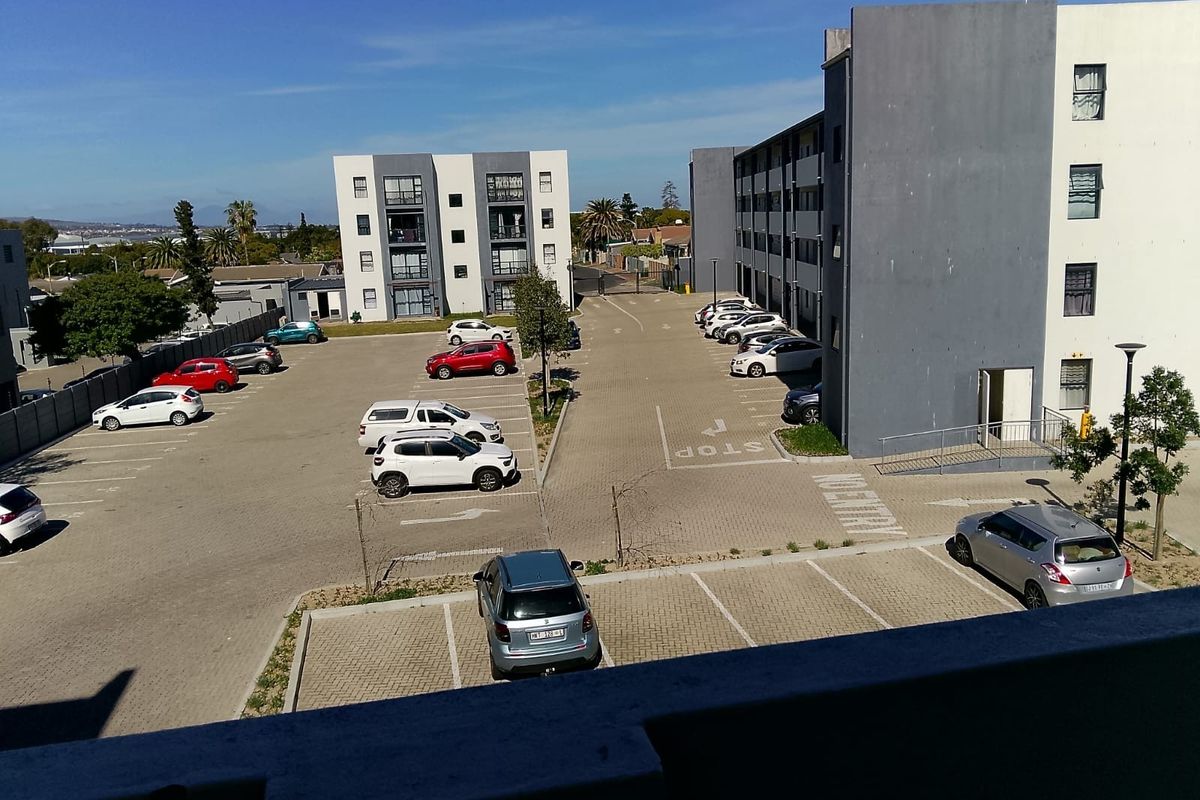 An elevated view of an apartment complex parking lot and surrounding residential building facades.