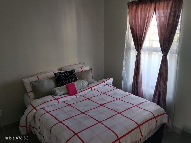 A bedroom featuring a window with installed curtain rods and neutral wall finishes.