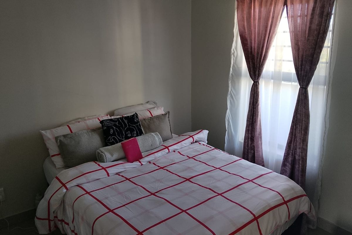 A bedroom featuring a window with installed curtain rods and neutral wall finishes.