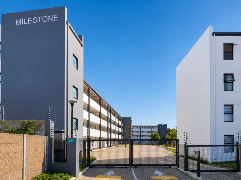 Front entrance view of the Milestone apartment complex, featuring modern multi-story buildings, secure gated access, and paved driveway infrastructure.