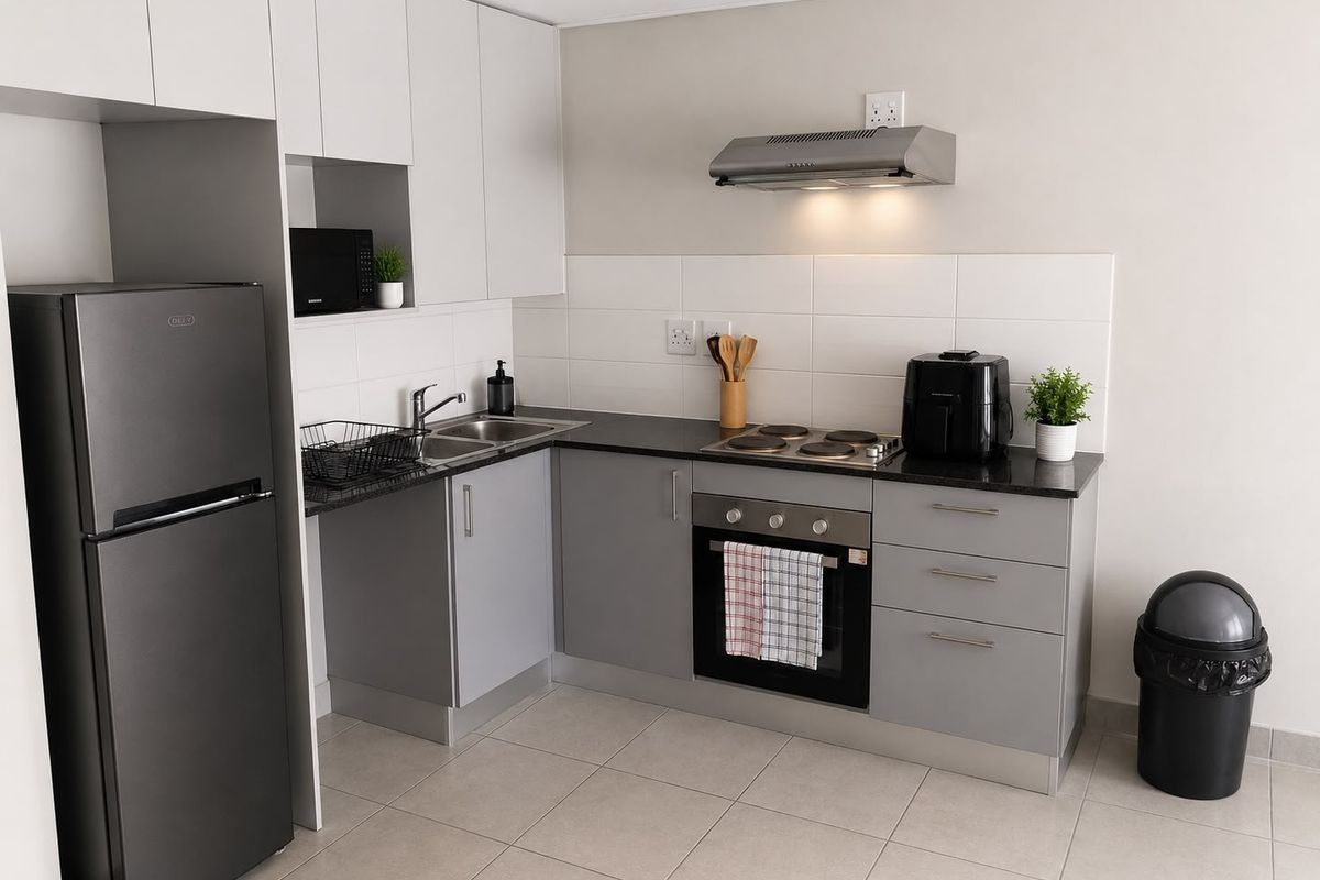 Modern kitchen featuring grey and white cabinetry, dark countertops, built-in oven, electric hob, extractor fan, and tiled flooring.