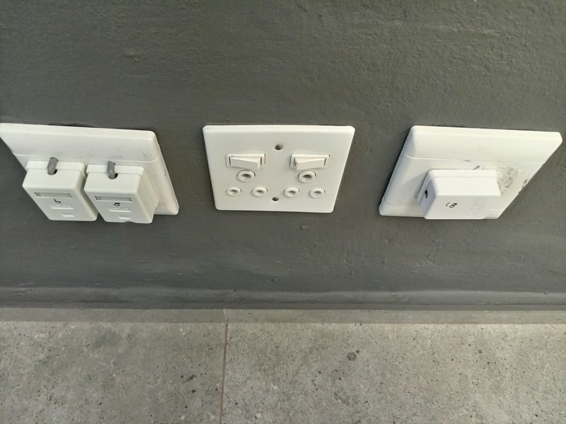 Close-up view of electrical and data wall sockets mounted on a grey painted wall above tiled flooring.