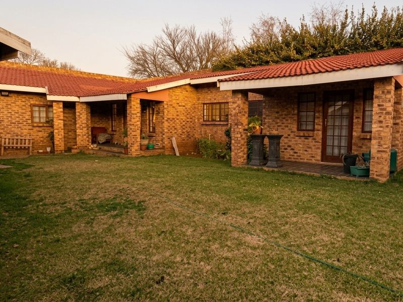 A rear view of the house featuring a face brick facade, a tiled roof, and a covered patio area overlooking the garden.
