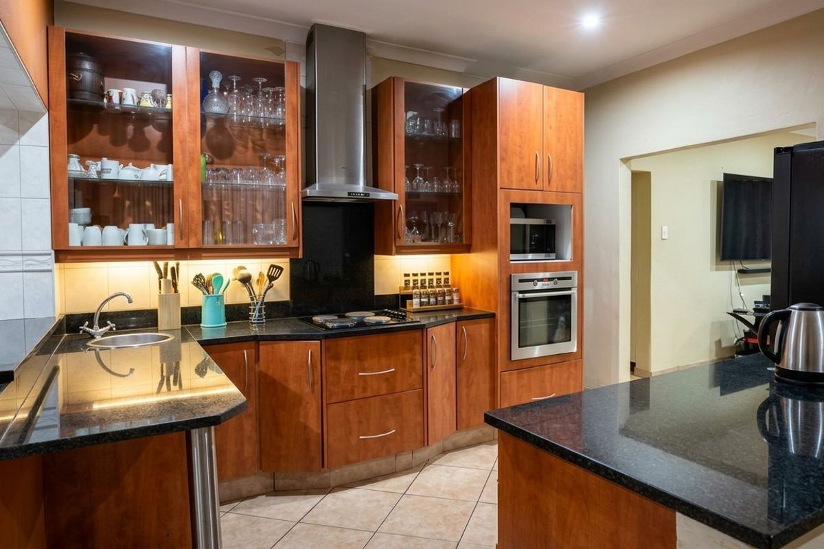 A well-maintained kitchen featuring warm wood cabinetry, granite countertops, built-in appliances, and integrated under-cabinet lighting for a functional workspace.