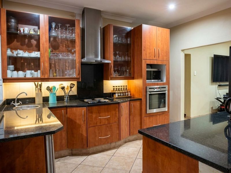 A well-maintained kitchen featuring warm wood cabinetry, granite countertops, built-in appliances, and integrated under-cabinet lighting for a functional workspace.