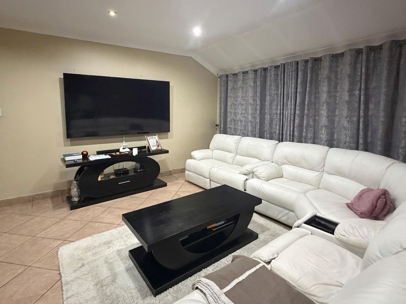 A comfortable living room featuring ceramic floor tiles, recessed downlighting, and a coved ceiling, providing a functional and well-lit space for relaxation.