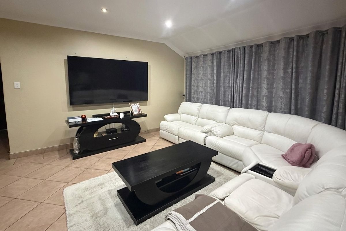 A comfortable living room featuring ceramic floor tiles, recessed downlighting, and a coved ceiling, providing a functional and well-lit space for relaxation.