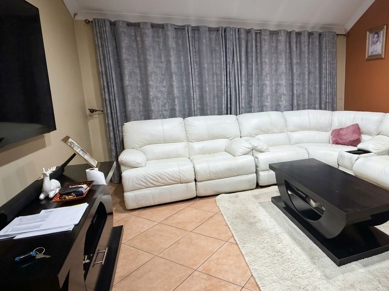 A comfortable living room featuring tiled flooring and a vaulted ceiling, providing a functional and inviting space for relaxation.