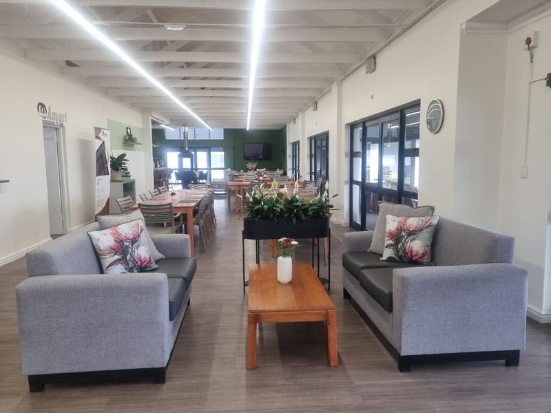 Spacious open-plan communal area featuring exposed beam ceilings, modern linear lighting, and large sliding glass doors providing ample natural light.