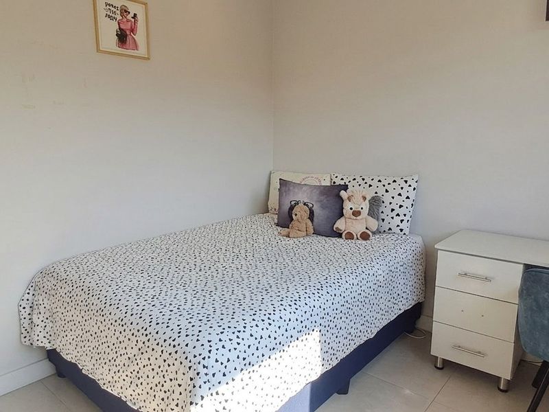A compact bedroom featuring tiled flooring and a built-in desk area, providing a functional space for rest and study.