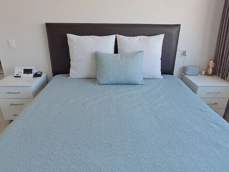 A well-maintained bedroom featuring neutral wall finishes, tiled flooring, and large windows with curtain tracks, offering a clean and functional living space.