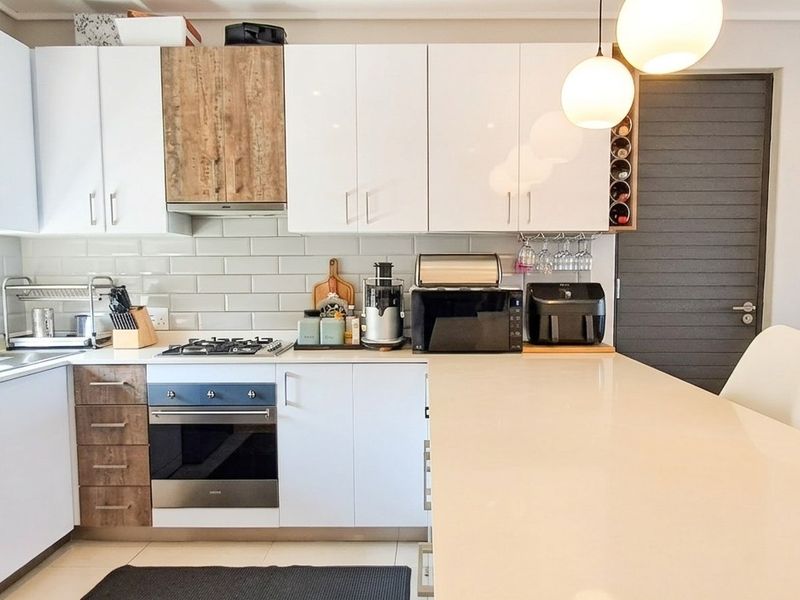 Modern kitchen featuring white cabinetry, quartz countertops, a central island, gas hob, and subway tile backsplash in a clean, contemporary design.