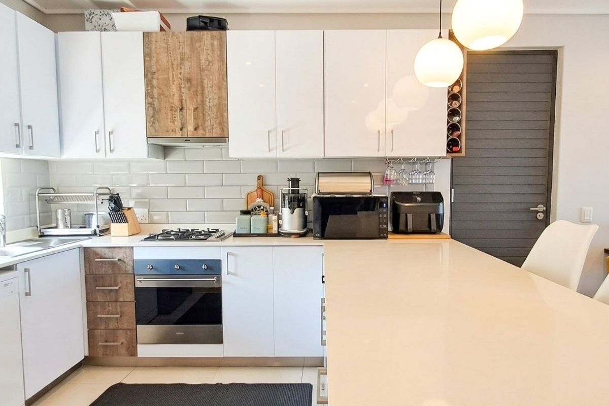 Modern kitchen featuring white cabinetry, quartz countertops, a central island, gas hob, and subway tile backsplash in a clean, contemporary design.