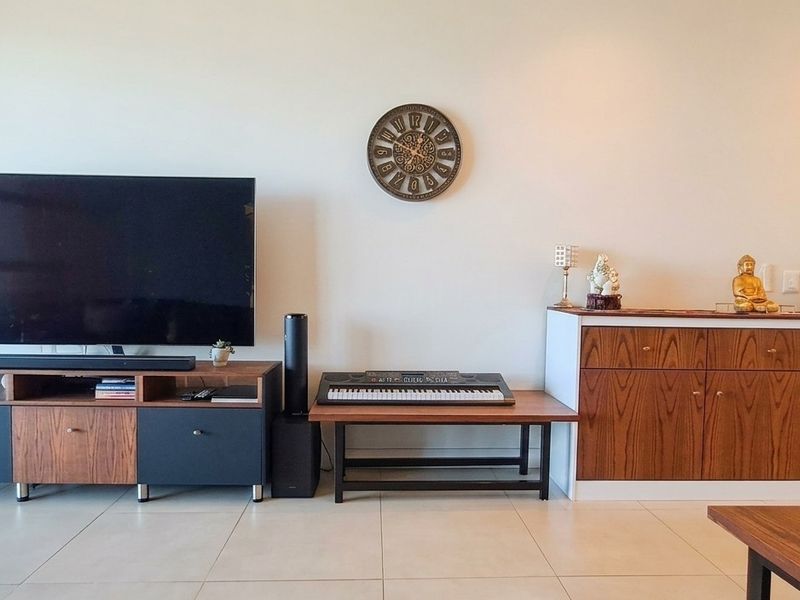A well-maintained living area featuring neutral tiled flooring, modern built-in cabinetry, and recessed ceiling lighting, creating a clean and functional space.