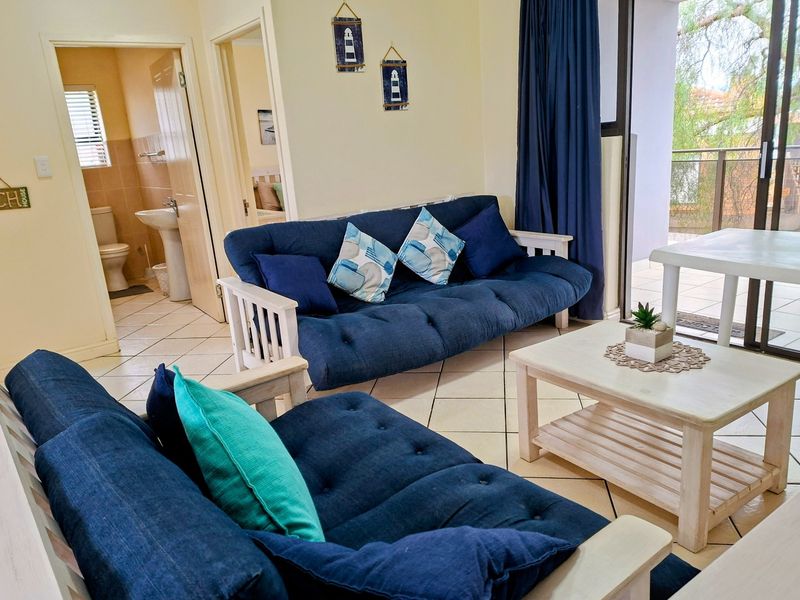 Open-plan living area featuring ceramic floor tiles, direct access to a balcony, and an adjacent bathroom with a pedestal sink and toilet.