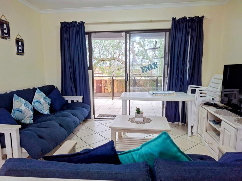 A living room featuring tiled flooring and a large sliding glass door providing access to an outdoor balcony area.