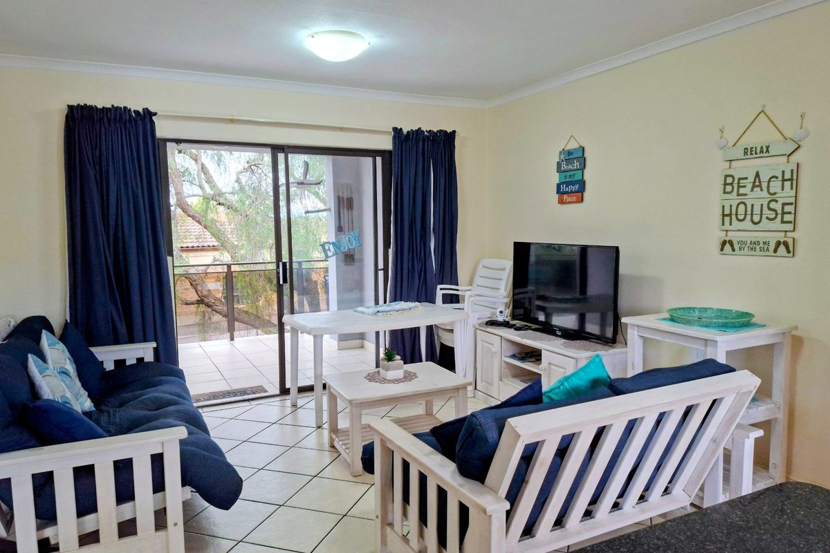 A bright living room featuring tiled flooring and large sliding glass doors that provide direct access to an outdoor balcony area.