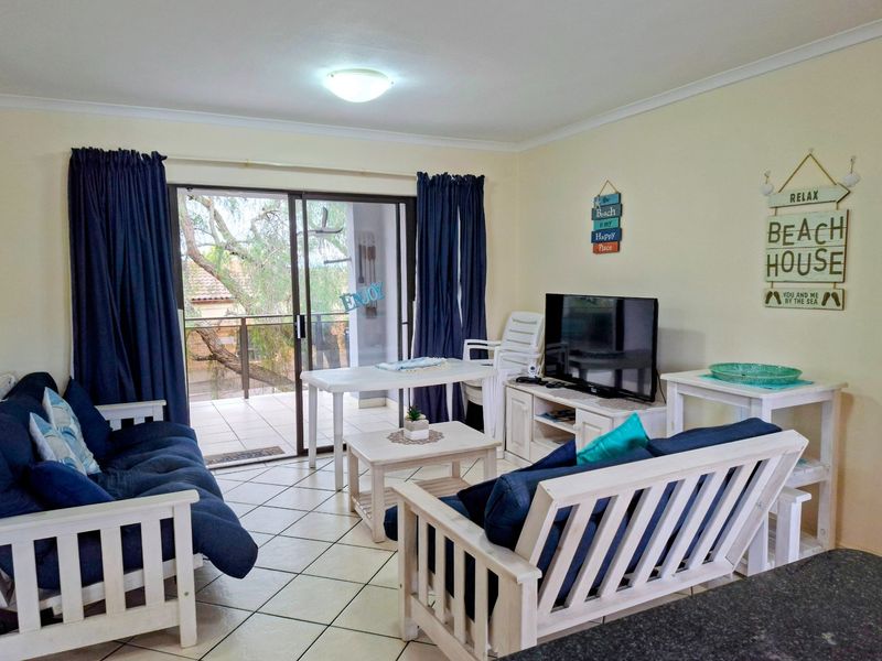 A bright living room featuring tiled flooring and large sliding glass doors that provide direct access to an outdoor balcony area.