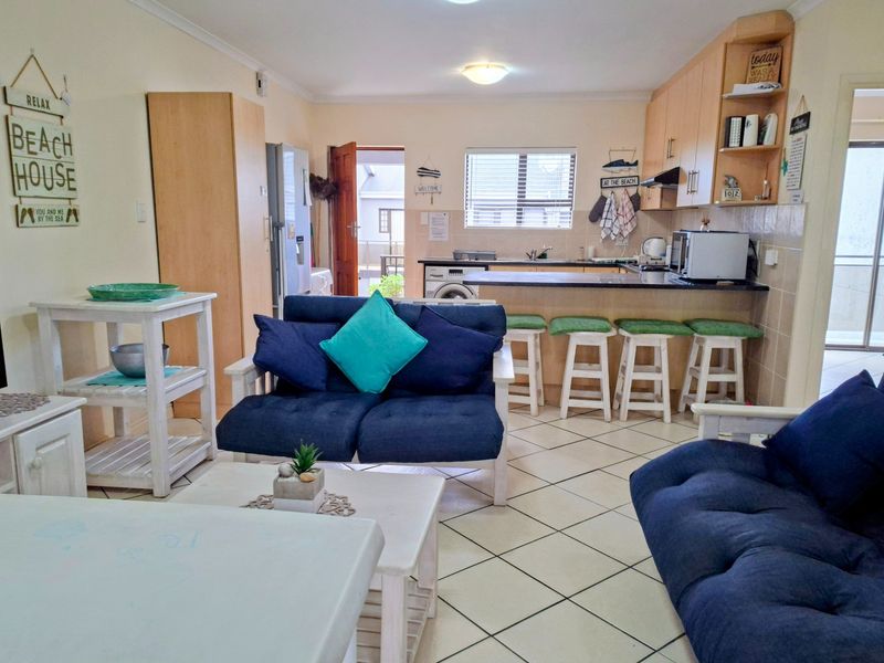 Open-plan living and kitchen area featuring tiled flooring, built-in cabinetry, and a breakfast bar, creating a functional and connected living space.