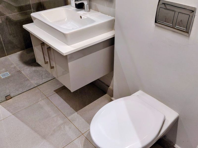 Modern bathroom featuring a wall-mounted vanity with basin, wall-hung toilet with concealed cistern, and a tiled walk-in shower area.