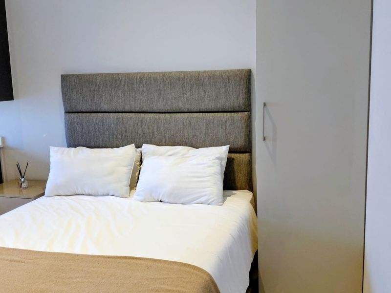 A clean bedroom featuring a modern upholstered headboard and a built-in wardrobe with a neutral finish.