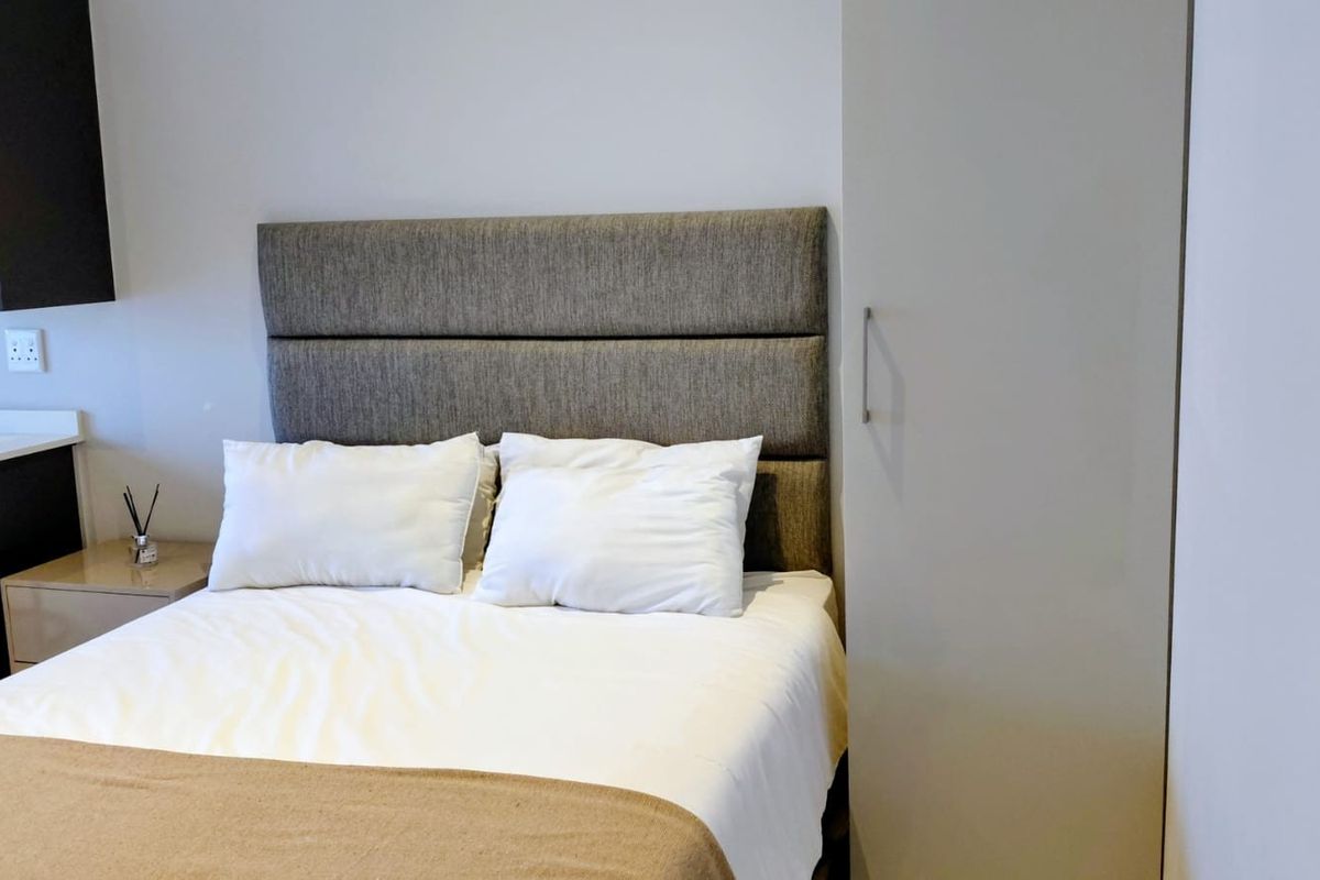 A clean bedroom featuring a modern upholstered headboard and a built-in wardrobe with a neutral finish.