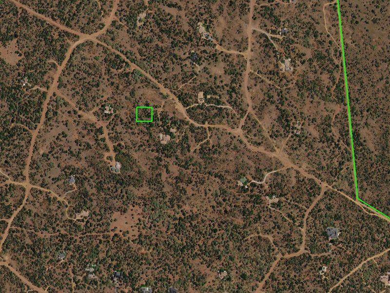 An aerial view of a vacant residential land plot surrounded by natural bushveld and existing rural residential properties.