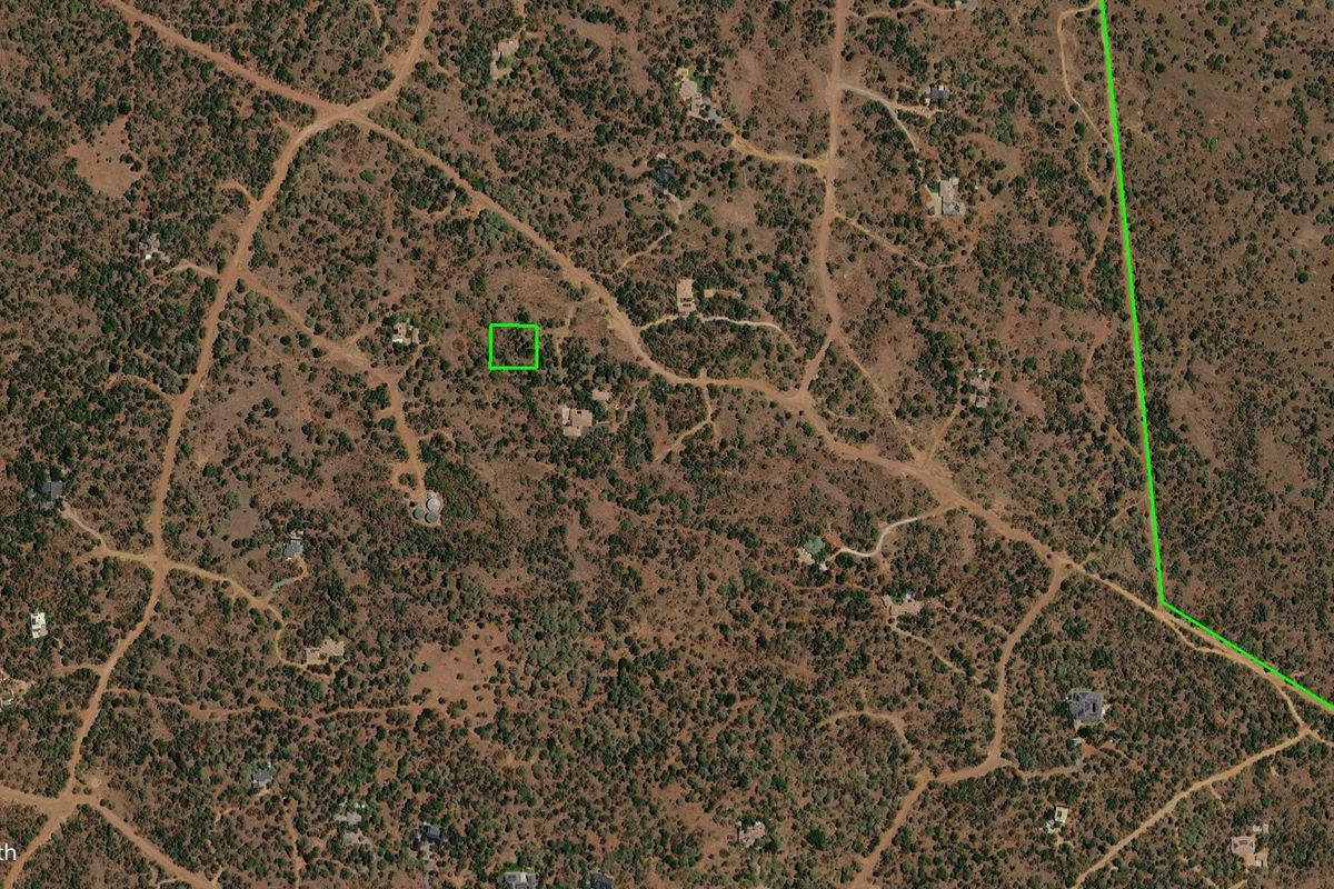 An aerial view of a vacant residential land plot surrounded by natural bushveld and existing rural residential properties.
