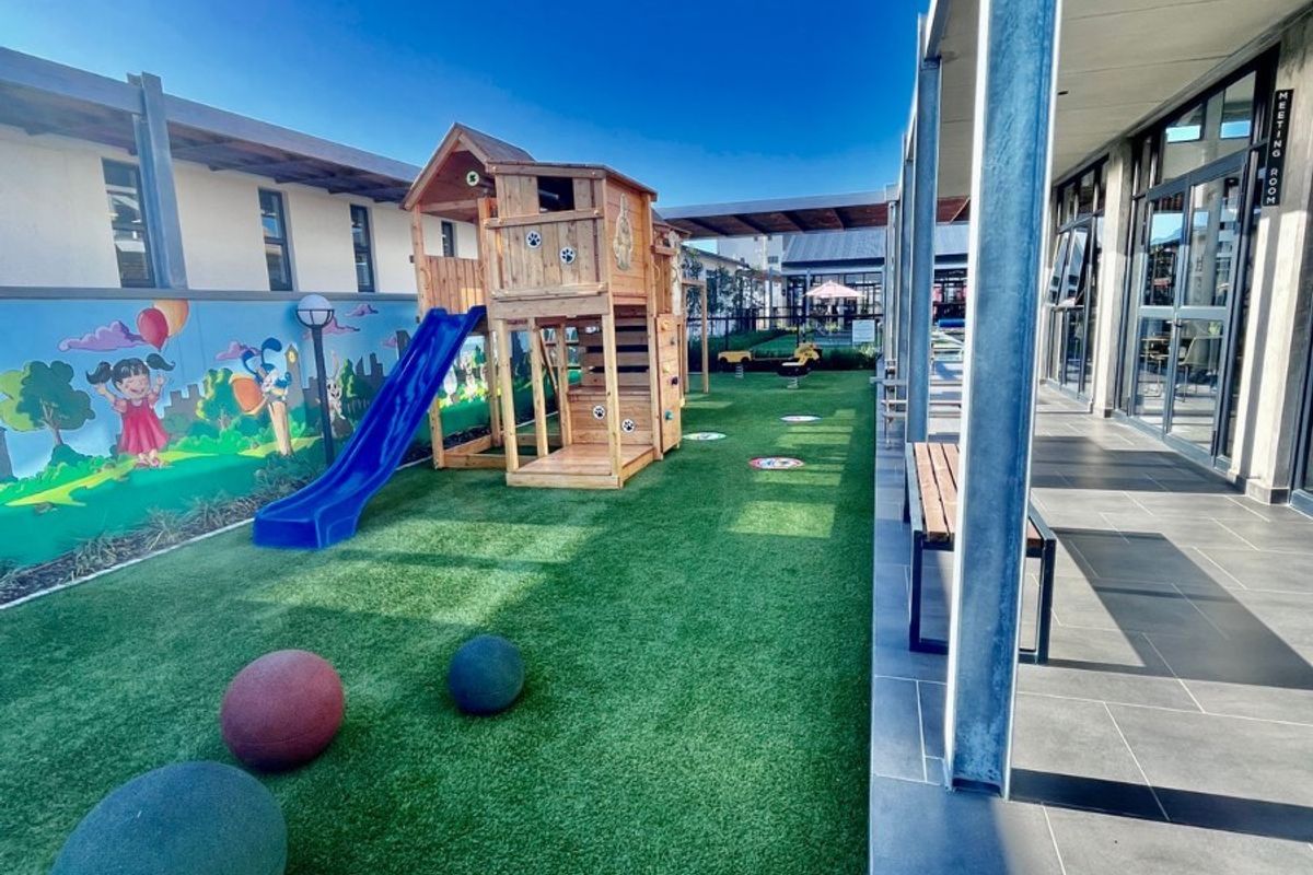 A well-maintained outdoor play area featuring artificial turf, a children's play structure, and a covered patio with tiled flooring.